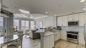 Een moderne keuken met witte kastjes, een centraal eiland en uitzicht op de oceaan.