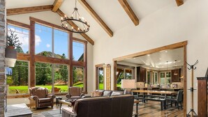 A spacious living room with a large window, a fireplace, and a dining area. - Brand New Golf Course Stunner! Short Walk to the Winery * Hot Tub * Fire Pit (Cle Elum)