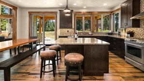 A modern kitchen with a large island, dark wooden cabinets, and a stone backsplash. - Brand New Golf Course Stunner! Short Walk to the Winery * Hot Tub * Fire Pit (Cle Elum)