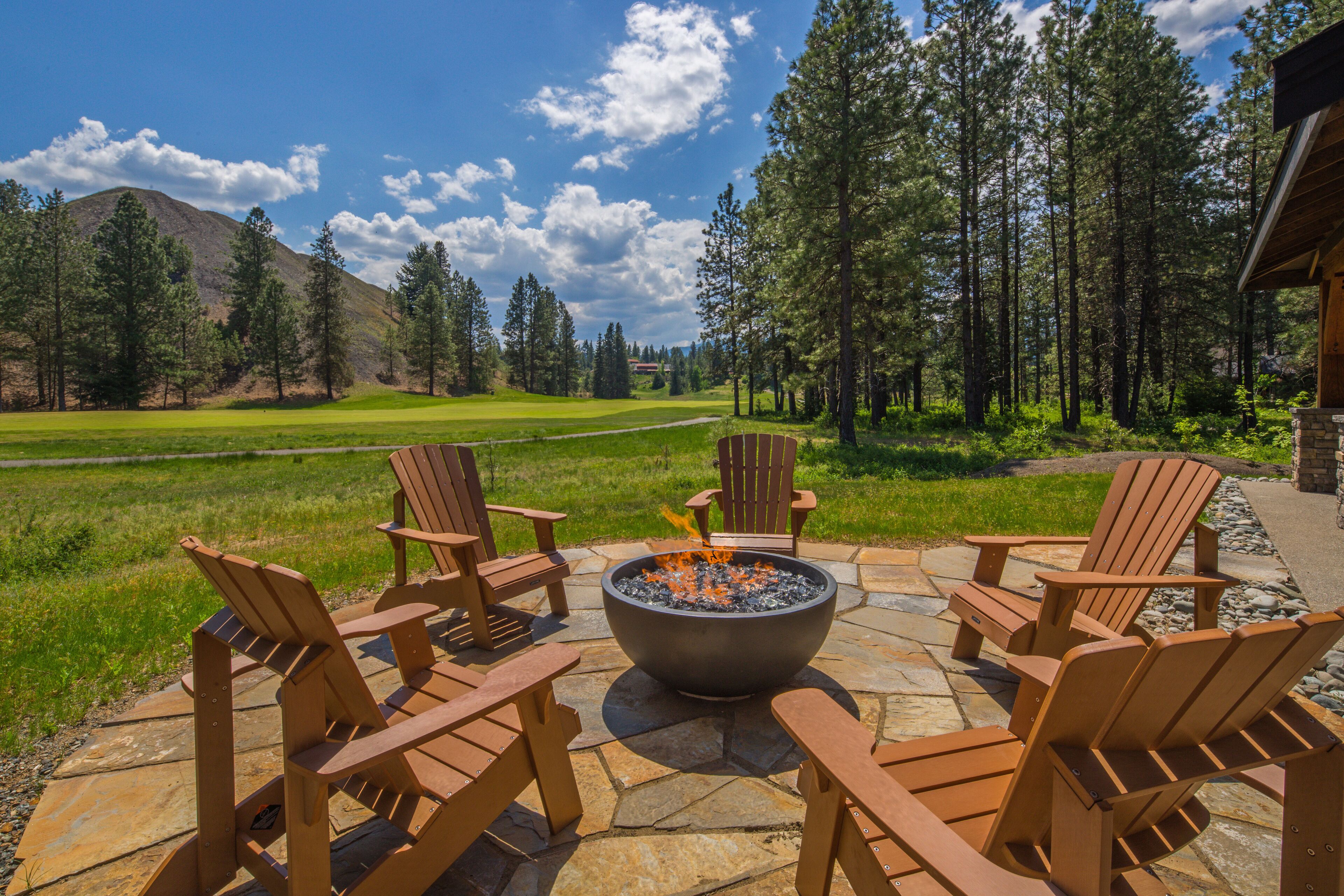 A patio with Adirondack chairs and a stone fire pit.