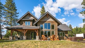 A two-story log cabin with a covered porch, stone fireplace, and outdoor seating. - Brand New Golf Course Stunner! Short Walk to the Winery * Hot Tub * Fire Pit (Cle Elum)