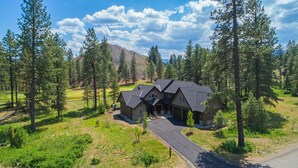 A large, two-story house with a dark roof, surrounded by a forest and a mountain in the background. - Brand New Golf Course Stunner! Short Walk to the Winery * Hot Tub * Fire Pit (Cle Elum)