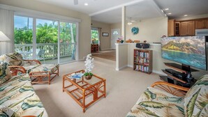 A spacious living area with a balcony, a dining area, and a kitchen. - Regency 910 Sweet Escape By Suite Paradise (Koloa)