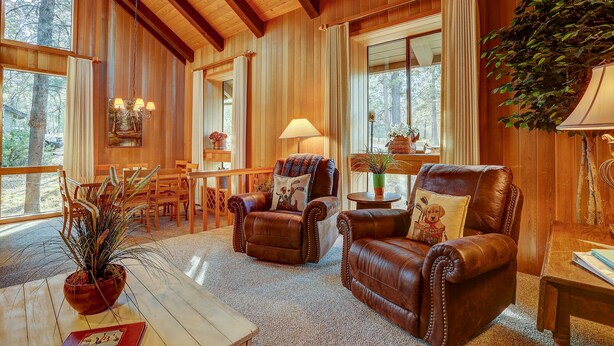 Een knusse woonkamer met leren fauteuils, een houten salontafel en een groot raam met uitzicht op het groen.