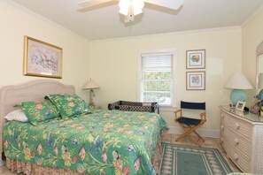 A bedroom with a bed, a dresser, a chair, and a window with blinds.