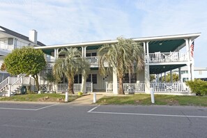 A two-story building with a covered porch and a flag.