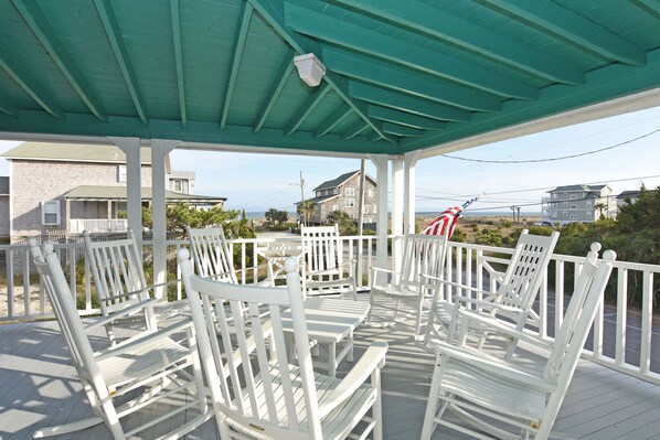 A covered outdoor seating area with white chairs and a green roof.