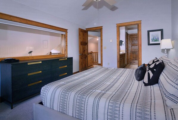 A bedroom with a bed, a dresser, a mirror, and a door leading to another room.