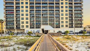 Een hotel met meerdere verdiepingen, balkons, een overdekte doorgang en een zandstrand.