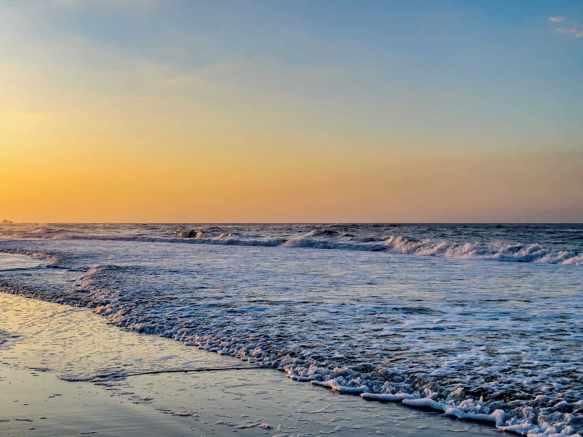 Een strand met golven in de zonsondergang.