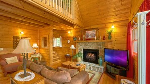 A cozy log cabin interior with a fireplace, a television, and a comfortable seating area. - Jacuzzi | Pigeon Forge | Pool Table | WiFi | Hot Tub (SEVIERVILLE)
