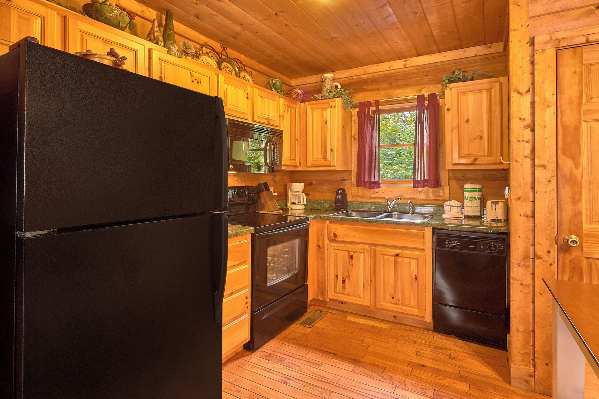 A kitchen with wooden cabinets, a black refrigerator, a stove, and a dishwasher.