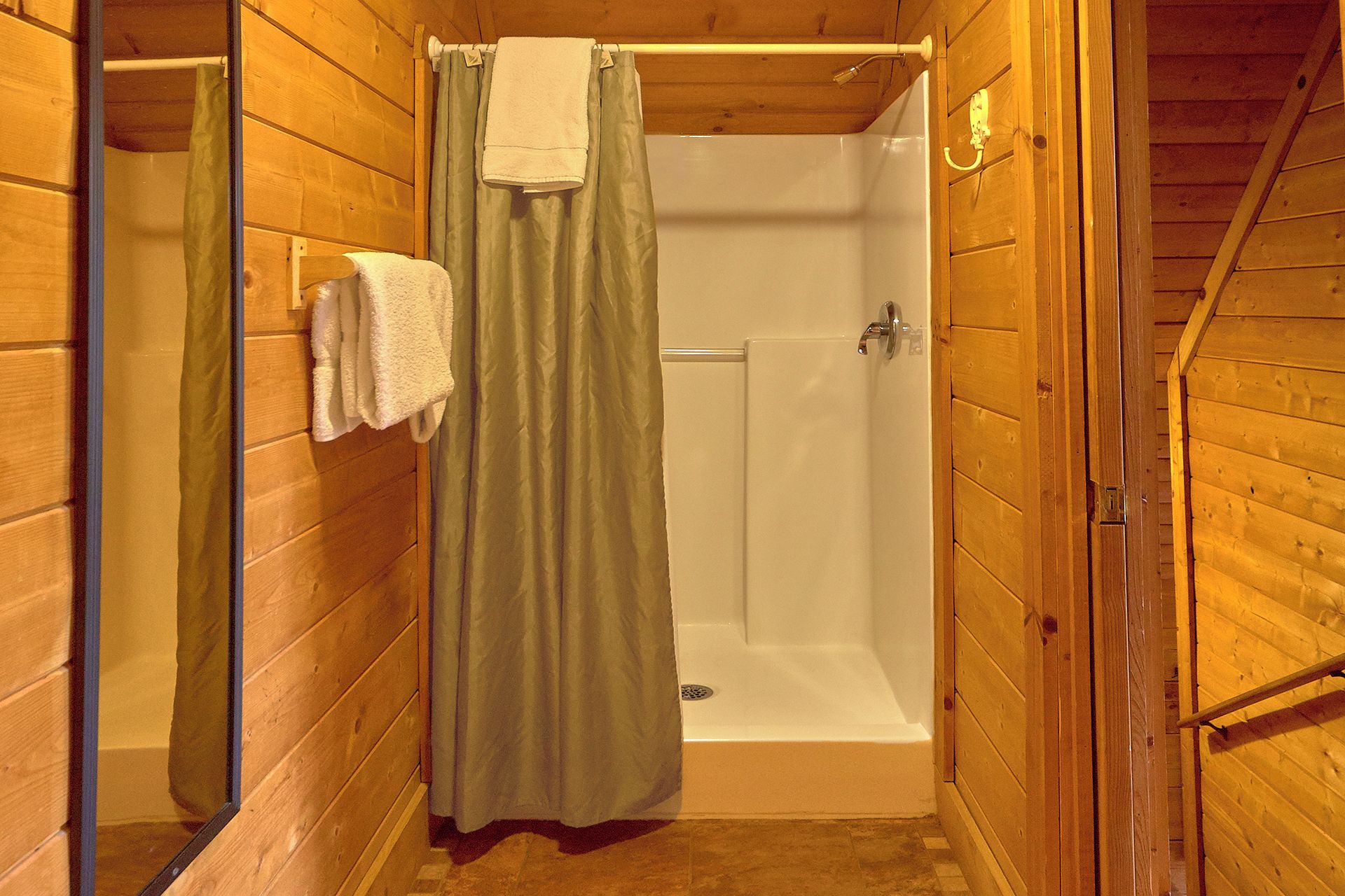 A wooden-paneled bathroom with a shower, a bathtub, and a toilet.