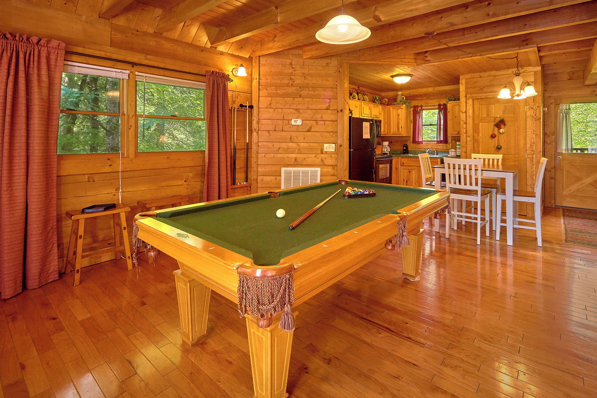 Un intérieur en bois comprenant une table de billard, un coin repas et une cuisine.