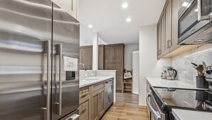 Une cuisine moderne dotée d’appareils électroménagers en acier inoxydable, de meubles en bois et d’un plan de travail en marbre.