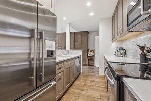 A modern kitchen with stainless steel appliances, wooden cabinets, and a marble countertop.