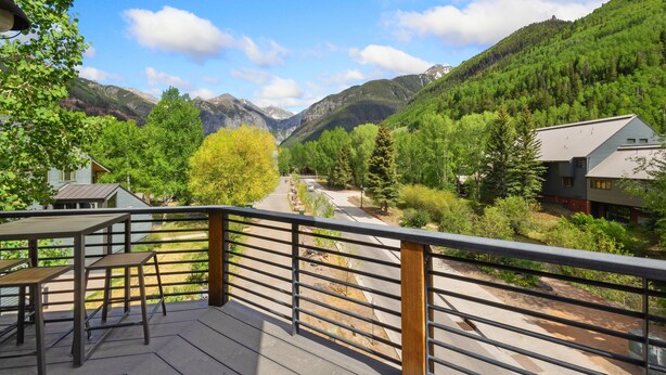 Un balcon donnant sur une vallée, des montagnes et une maison.