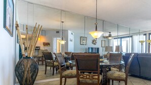 A dining area with a round table, chairs, and a large vase with bamboo sticks. - Summer House 703B - Great Beachfront Condo with Huge Balcony & Amazing Views! (Orange Beach)