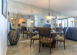 A dining area with a round table, chairs, and a large vase with bamboo sticks.