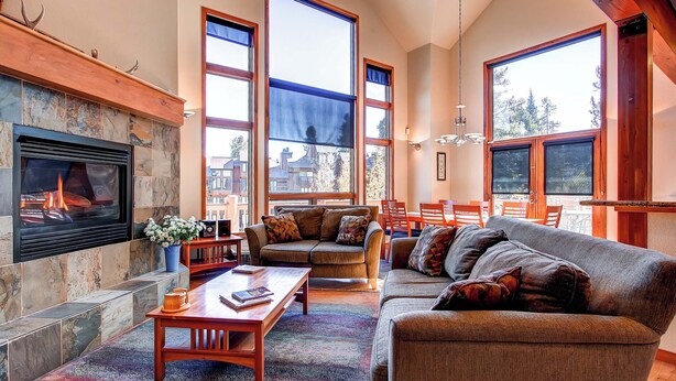 A spacious living room with a fireplace, large windows, and a cozy seating area. - Exquisite Home with Ski-In Access, PRIVATE HOT TUB, Stunning Views. FOUR (Breckenridge)