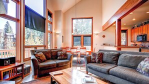 A spacious living room with large windows, a dining area, and a kitchen with wooden cabinets. - Exquisite Home with Ski-In Access, PRIVATE HOT TUB, Stunning Views. FOUR (Breckenridge)