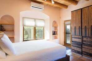 Ein Schlafzimmer mit Bett, Einbauschränken, einer Klimaanlage und einem großen Fenster.