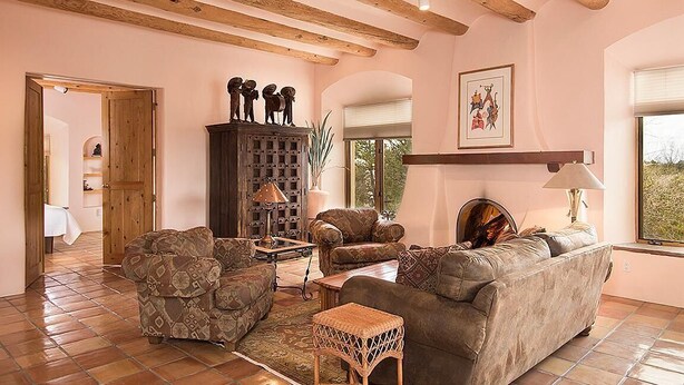 Een woonkamer met een bank, fauteuils, een houten kast en een groot raam.