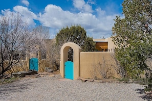 A building with a beige exterior, a turquoise door, and a clear blue sky. - North Hills Casa (Santa Fe)