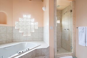 A bathroom with a bathtub, a shower, and a tiled wall with a geometric pattern.
