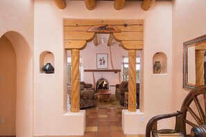 A cozy interior with a fireplace, wooden arches, and a rustic chair. - North Hills Casa (Santa Fe)