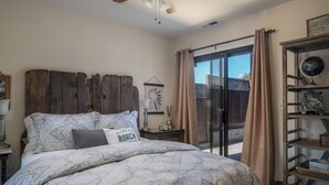 Ein Schlafzimmer mit einem großen Bett, einem Holzkopfende, einer Schiebetür zum Außenbereich und einem Regal mit Dekoration.