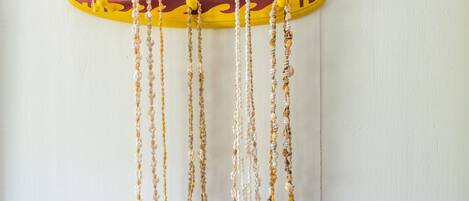 A surfboard-shaped wall hanging with multiple necklaces.