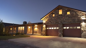 Une maison en pierre avec un garage, un porche à l’avant et une allée.