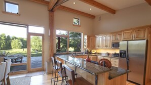 Une cuisine spacieuse dotée de meubles en bois, d’un réfrigérateur en acier inoxydable et d’un grand îlot central avec des tabourets de bar.