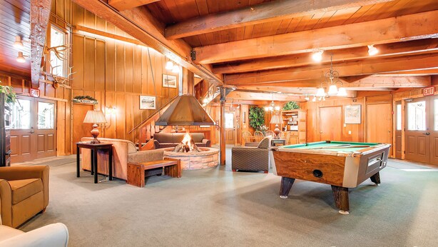 A cozy lodge interior with a pool table, comfortable seating, a fireplace, and wooden walls. - Completely Renovated, Downtown Studio - Top Floor Unit. Ski In Access | PM7D (Breckenridge)