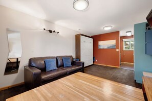 Una sala de estar moderna con un sofá de cuero, una mesa de centro de madera y un espejo grande.