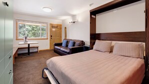 A bedroom with a bed, a desk, a chair, a sofa, and a wardrobe. - Completely Renovated, Downtown Studio - Top Floor Unit. Ski In Access | PM7D (Breckenridge)