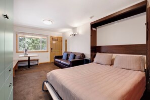 Um quarto com uma cama, escrivaninha, cadeira, sofá e guarda-roupa.