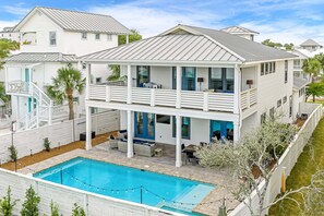 A two-story house with a swimming pool, outdoor seating, and a covered patio.