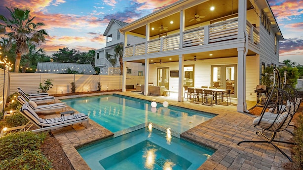 A two-story house with a swimming pool, outdoor seating, and a balcony.