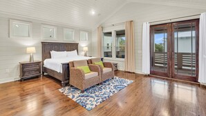 A bedroom with a bed, two nightstands, a ceiling fan, and a large window with curtains.