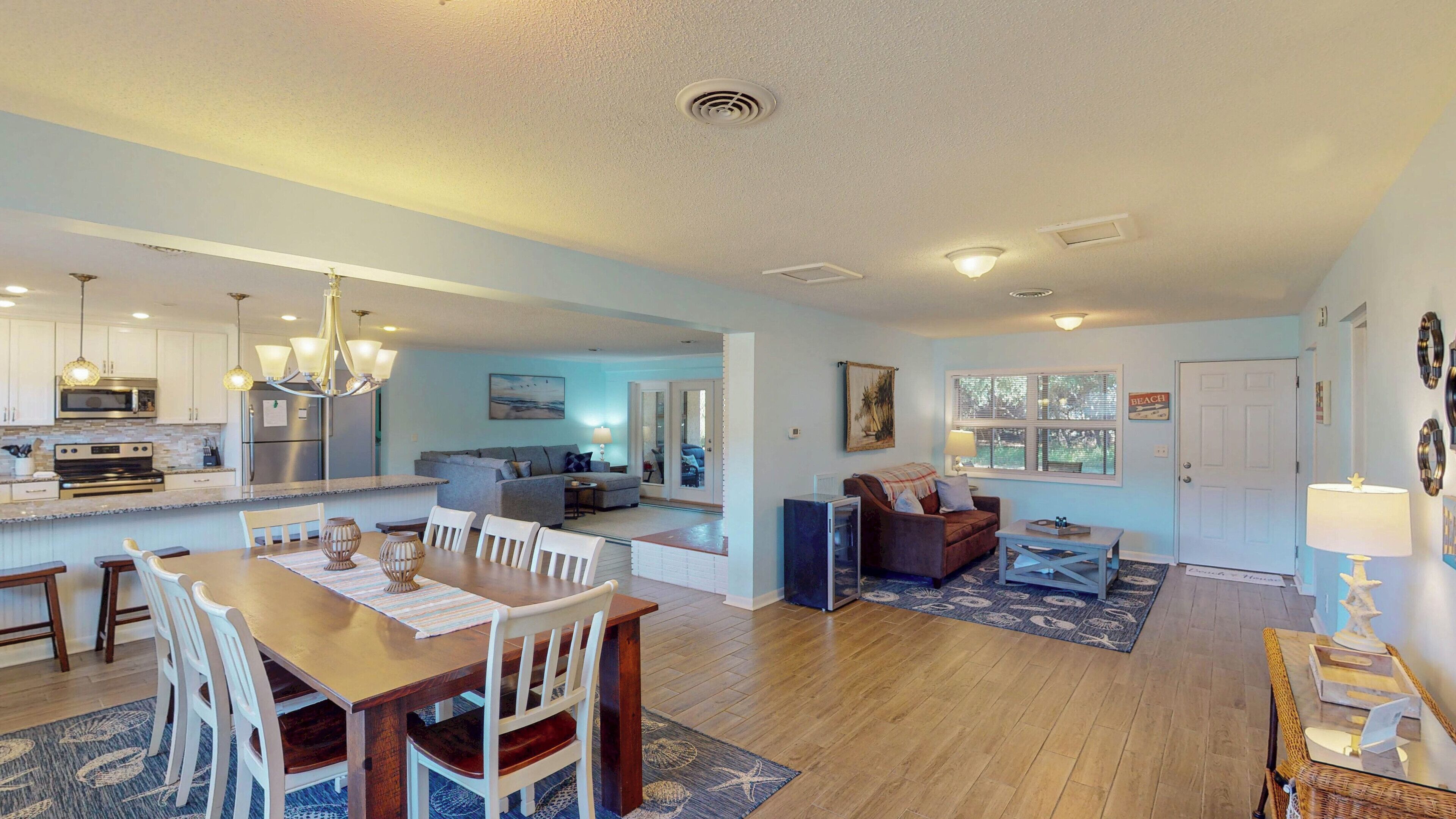 A spacious living area with a dining table, chairs, and a kitchen in the background.