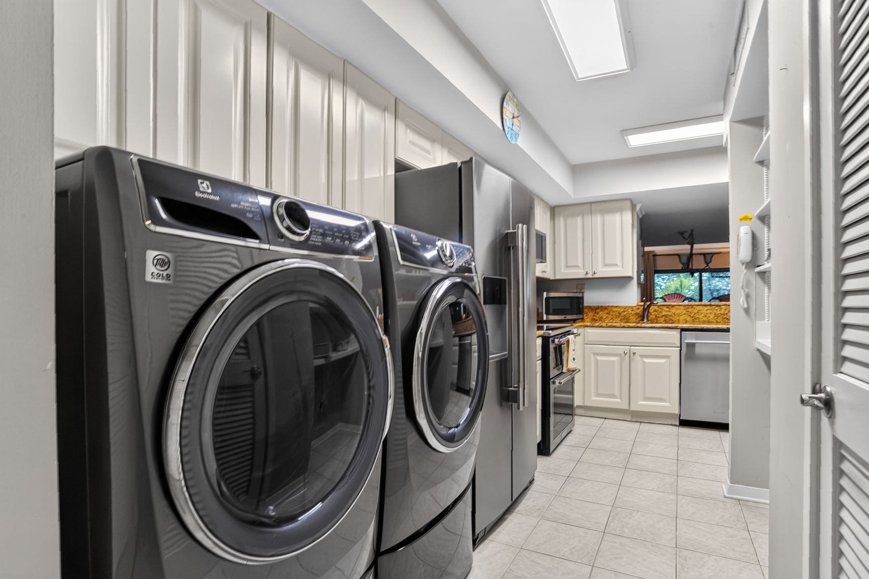A laundry room with two front-loading washing machines and a refrigerator.