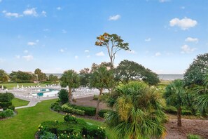 A landscaped area with a swimming pool, lounge chairs, and a view of the sea.
