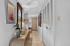 Un couloir avec un banc, une lampe, un tableau encadré et une porte.