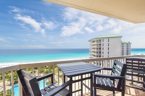 A balcony with a view of the ocean and a hotel building. - Brightly colored beachfront condo w/private balcony! 🏖️ (Destin)