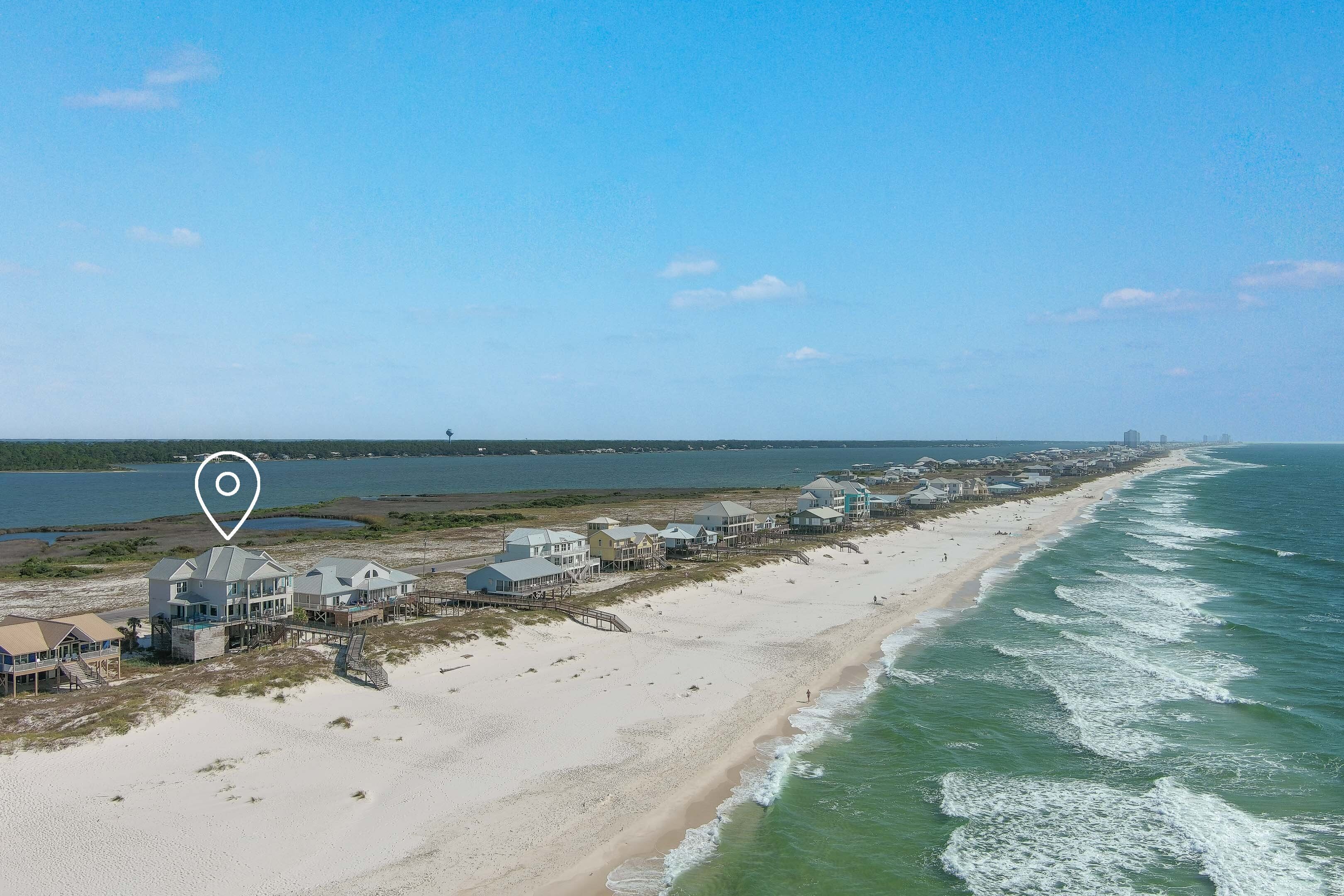 Une propriété située sur la côte, comprenant plusieurs maisons le long de la plage, une jetée et une vue sur l’océan.