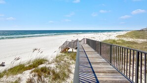 Una passerella di legno che conduce a una spiaggia di sabbia bianca e vista sull'oceano.