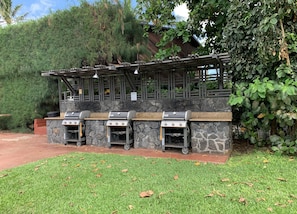 Área de churrasco com três grelhadores e um painel de parede de pedra.