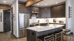 Una cocina moderna con armarios de madera oscura, electrodomésticos de acero inoxidable y una isla central con taburetes de bar.